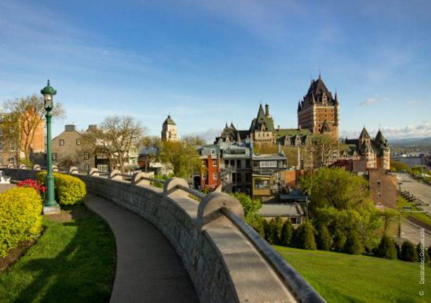 Entdecken Sie diesen Kanada Road Trip: Panoramaansicht von Quebec mit historischen Gebäuden und einer Mauer im Vordergrund. 