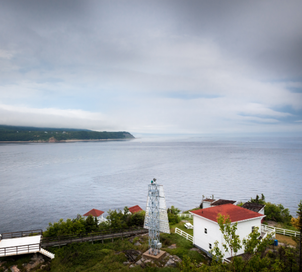 Leuchtturm in Tadoussac mit Blick auf das ruhige Wasser und die umliegende Küstenlandschaft. Kanada-Rundreise