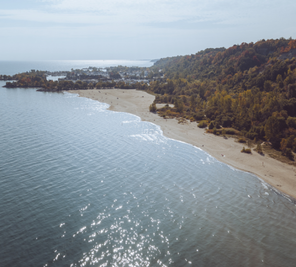 Blick auf einen Strand am Ontariosee mit sanften Wellen und bewaldeten Ufern im Hintergrund. Kanada-Rundreise