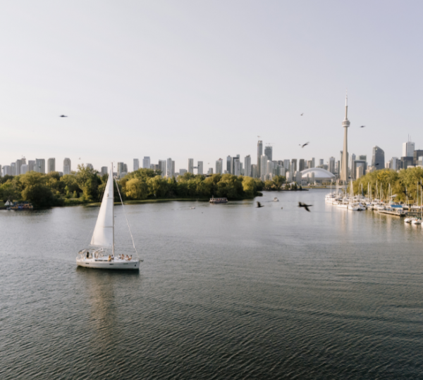 Ostkanada Urlaub. Segelboot auf einem ruhigen Gewässer mit der Skyline von Toronto im Hintergrund und einem klaren Himmel. Kanada-Rundreise