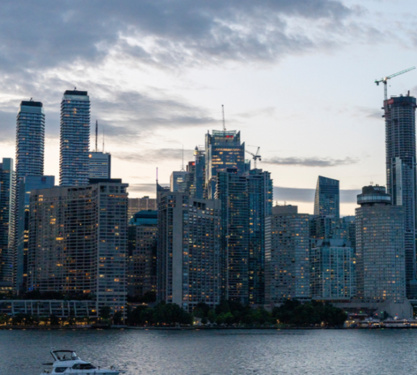 Skyline von Toronto mit modernen Wolkenkratzern und einem Boot im Vordergrund während der Dämmerung. Kanada-Rundreise
