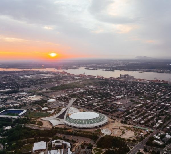Luftaufnahme von Montreal mit dem Olympiastadion und dem Fluss im Hintergrund während des Sonnenuntergangs. Kanada-Rundreise