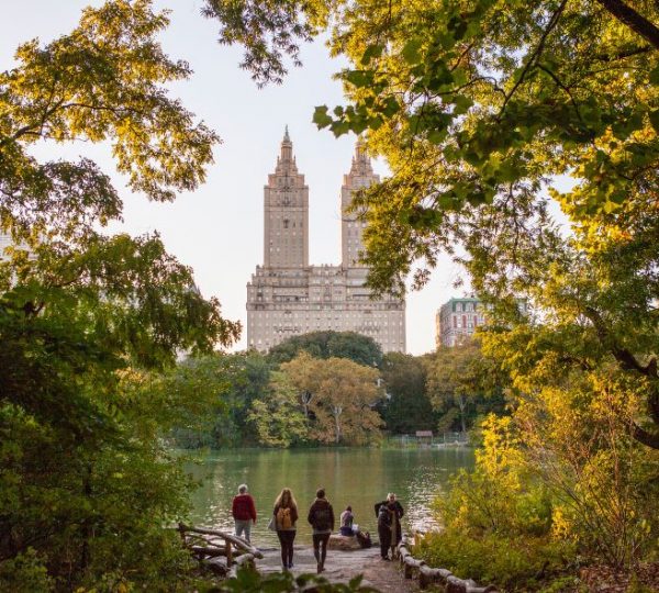 Zwei hohe Gebäude im Hintergrund, umgeben von Bäumen und einem See im Central Park. Kanada-Rundreise