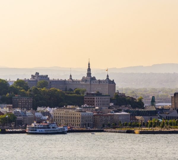 Kanada Selbstfahrer Rundreise. Panoramaansicht der Stadt Quebec mit einem historischen Gebäude und einem Schiff im Vordergrund. Kanada-Rundreise