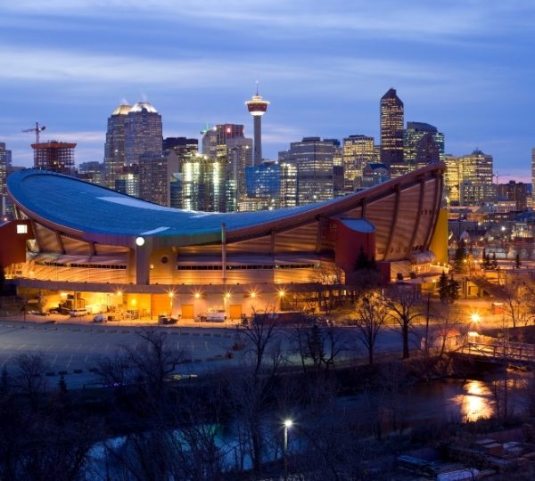 Saddledome in Calgary, umgeben von der Skyline der Stadt bei Dämmerung. Kanada-Rundreise