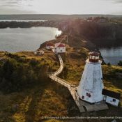 Leuchtturm von Swallowtail auf Grand Manan, umgeben von Wasser und Natur, mit einem Holzsteg, der zum Gebäude führt. Kanada-Rundreise
