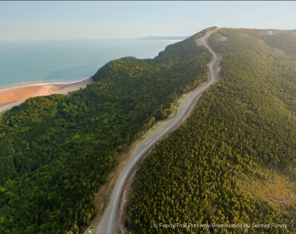 Luftaufnahme des Fundy Trail Parkway mit einer kurvenreichen Straße und bewaldeten Hügeln in der Umgebung. New Brunswick