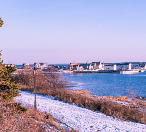 Prince Edward Island Winterküste: bunte Hafenhäuser am ruhigen Meer, weiße Schneedecke am Ufer, ruhige Küstenlandschaft Kanada-Rundreise