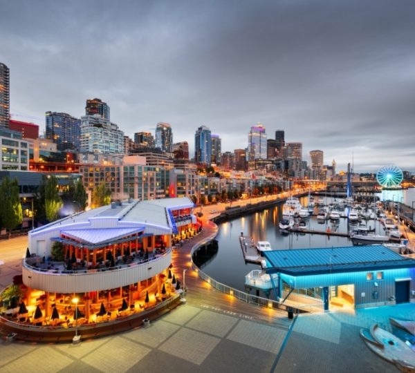 NCL Encore Kreuzfahrtschiff vor der Hafen- und Stadtlandschaft von Seattle mit Marina, Abendlicht und Skyline, Vancouvers Waterfront-Charakter sichtbar Kanada-Rundreise