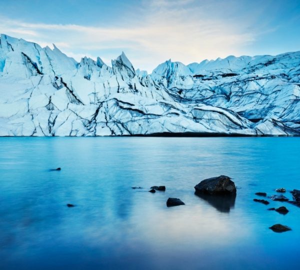 Alaska-Gletscherlandschaft mit blauem Wasser, eisiger Eisfront, rockige Ufer im Vordergrund und tiefe Blautöne – eine ruhige, eindrucksvolle Küstenlandschaft Kanada-Rundreise