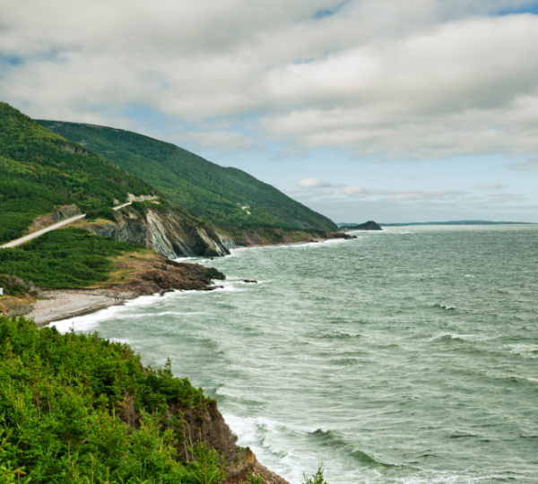 Ansicht der Cape Breton Highlands mit grünen Hügeln, einer Küstenlinie und einer einsamen Straße, charakterisiert durch landschaftliche Küstenlandschaft und nachhaltige grüne Vegetation rund um Cape Breton Island Kanada-Rundreise