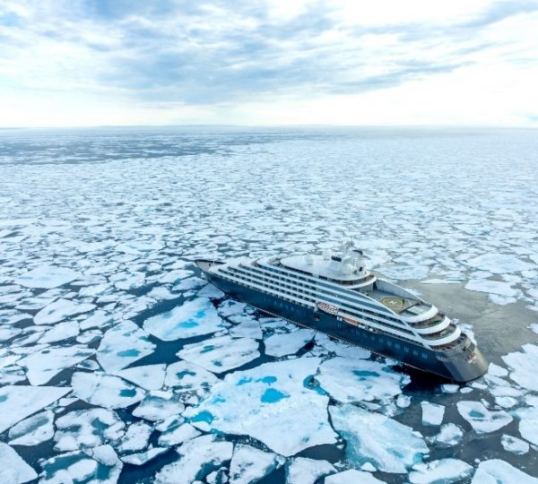 Scenic Eclipse kreuzt durch eine Arktislandschaft mit bruchartigen Eisplatten und blau getönten Wasserflächen; majestätisches Kreuzfahrtschiff vor einer weiten Eislandschaft Kanada-Rundreise