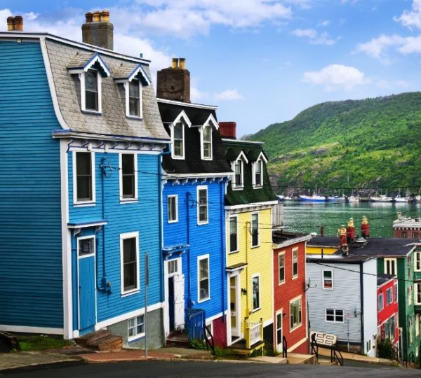 Bunte Häuserreihe in St. John’s, Newfoundland, mit blauen, gelben, roten Fassaden und Hafenlandschaft im Hintergrund; verknüpft mit Kanada Arktis Kreuzfahrt-Thema und Scenic Eclipse Kanada-Rundreise