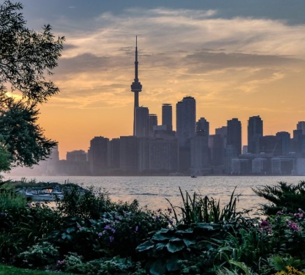 Toronto Skyline bei Sonnenuntergang mit CN Tower, Wasser im Vordergrund, lebendige Gartenlandschaft im Vordergrund, Scenic Eclipse Kreuzfahrt Kanada Arktis Kanada-Rundreise