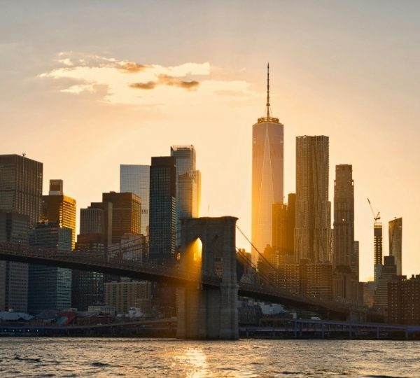 New York City Skyline mit der Brooklyn Bridge im golden leuchtenden Sonnenuntergang, Blick über den East River, markante Wolkenkratzer ragen im Licht der Abendsonne empor Kanada-Rundreise