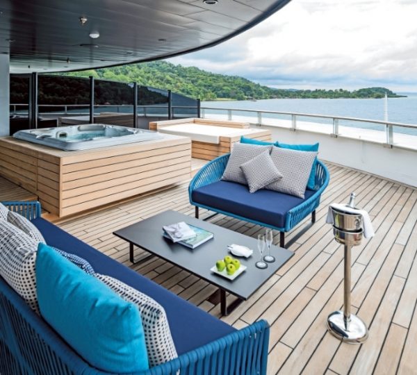 Luxuriöses Deck der Scenic Eclipse mit blauen Loungemöbeln und Sitzkissen, Blick auf arktische Küste und Kanadas Hudson Bay; Terrasse auf einem Kreuzfahrtschiff Kanada-Rundreise