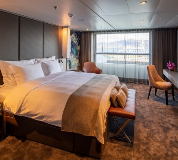 Luxuriöse Kabine mit großem Bett, cremefarbenen Decken und Panorama-Fenstern, Blick auf Wasser und Hafen – Scenic Eclipse Kreuzfahrtkabine in moderner Ausstattung Kanada-Rundreise