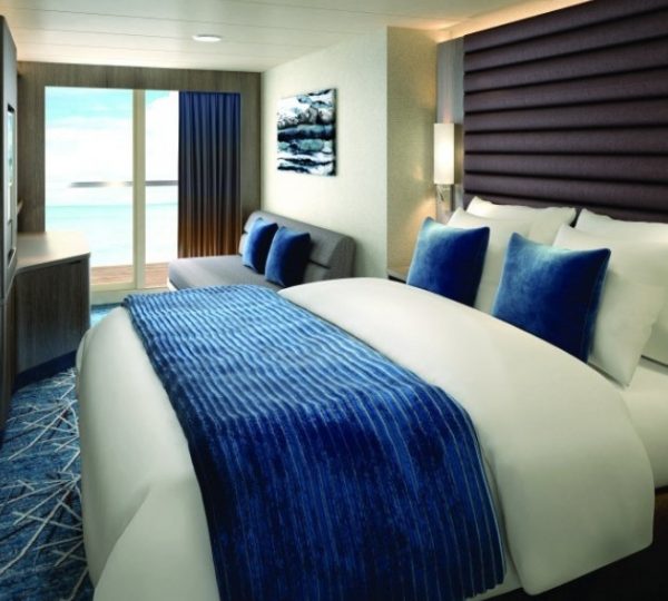 Kabinenszene auf der NCL Encore in Alaska: großes Bett mit blauem Überwurf, weiße Kissen, dunkle Kopfstütze, Balkonblick aufs Meer Kanada-Rundreise