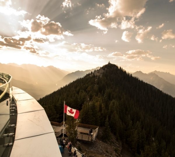 Rocky Mountaineer Aussicht in Kanada mit Berglandschaft, Sonnenuntergang, kanadischer Flagge am Aussichtspunkt, Vancouver-Kreuzfahrt-Kontext Kanada-Rundreise