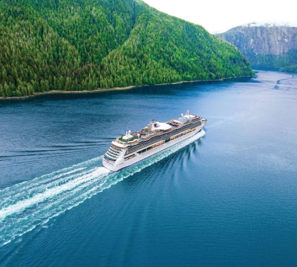 Rocky Mountaineer Kreuzfahrt: Großes Kreuzfahrtschiff fährt durch einen Fjord, umgeben von grünen Bergen und blauem Wasser Kanada-Rundreise