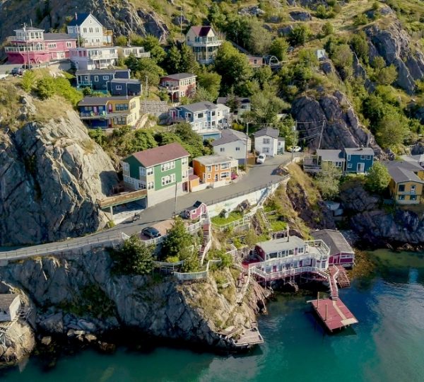 Saint John farbenfrohe Häuser am felsigen Küstenhang, malerische Hafenanlage, dichter Grünwald, ruhiges Meer im Vordergrund Kanada-Rundreise