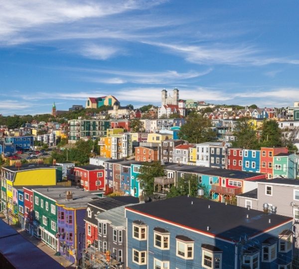 St. John's, Newfoundland: farbenfrohe Reihenhäuser am Hang mit roten, grünen und blauen Fassaden, Küstenblick, malerische Hafenatmosphäre und klarer Himmel Kanada-Rundreise