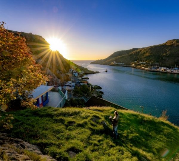 Sonnenuntergang über einer ruhigen Bucht mit Küstenlinien, Hügeln und kleinen Häusern in St. John’s; warme Strahlen, klarer Himmel, friedliche maritime Szenerie Kanada-Rundreise