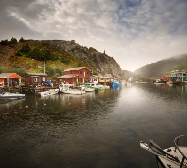 Saint John Hafen in New Brunswick mit bunten Fischerhäusern, felsiger Küstenlandschaft und Booten im Wasser, ruhiger Himmel über Bergen Kanada-Rundreise