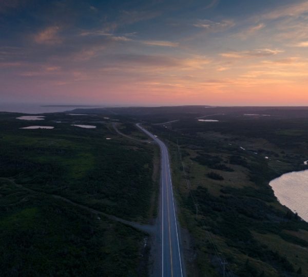 L'Anse-au-Clair Küstenstraße bei Sonnenuntergang, weite grüne Küstenlandschaft, ruhiges Wasser im Abendlicht, typisches Atlantik-Feeling der Atlantikprovinzen Kanada-Rundreise