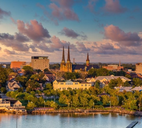 Charlottetown Skyline mit zwei markanten Kirchtürmen, viktorianischen Gebäuden am Wasser und warmem Abendlicht über der Küstenlinie von Prince Edward Island Kanada-Rundreise