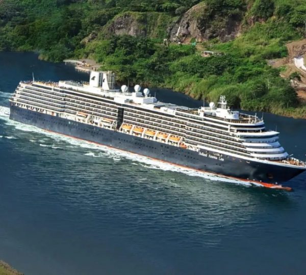 Großes blaues Kreuzfahrtschiff Zuiderdam der Holland America Line schneidet durch Wasser, weiß getünchte Decks, umgeben von grüner Küstenlandschaft Kanada-Rundreise