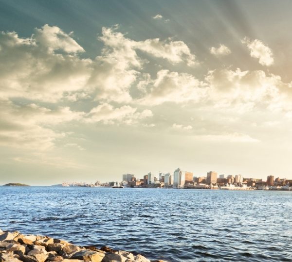 Halifax-Küstenpanorama mit ruhigem blauem Wasser, skyline am Ufer, wolkigem Himmel und warmem Abendlicht – Halifax, Kanada, beeindruckende Hafenlandschaft Kanada-Rundreise