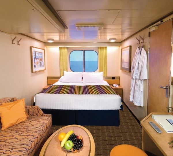 Kabinenszene auf der Zuiderdam: Doppelbett, Sofa, Obstteller, Fenster mit Meerblick, warme Holzoptik und helles Interieur Kanada-Rundreise