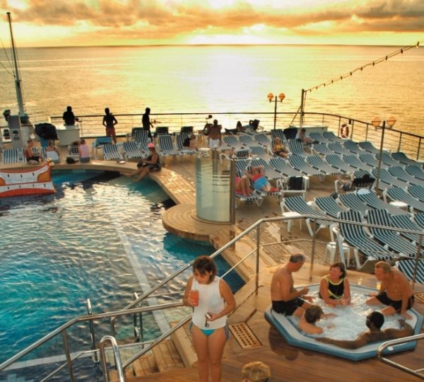 Zuiderdam Holland America Line Deckpool bei Sonnenuntergang über dem Meer, belebte Poollandschaft mit Liegestühlen, Menschen am Beckenrand und am Rand der Decks Kanada-Rundreise