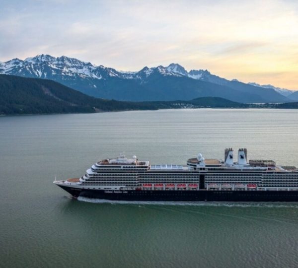 Nieuw Amsterdam Kreuzfahrtschiff vor einer schneebedeckten Berglandschaft in Alaska, klare See, eindrucksvolles Panorama der umliegenden Berge Kanada-Rundreise