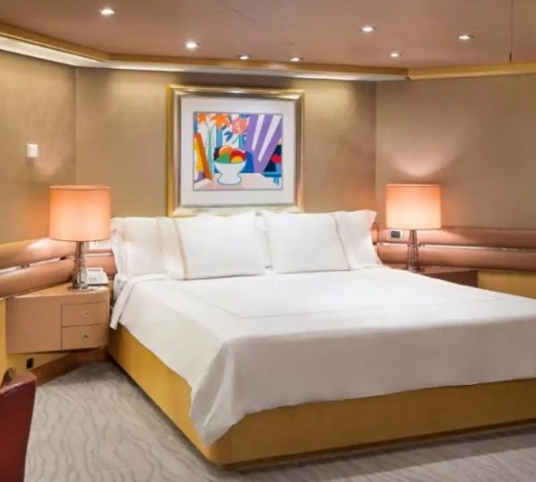 Kabine der Nieuw Amsterdam mit warmer Beleuchtung, großem Bett, hellem Dekor, zwei Nachttischenlampen, sanfter Farbgebung und farbigem Kunstwerk über dem Kopfteil ergänzt das maritime Ambiente. Kanada-Rundreise