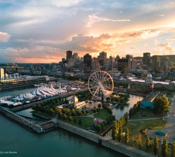 Im Alten Hafen von Montréal ragt das Grande Roue de Montréal bei goldenem Abendlicht über dem Ufer, im Hintergrund die Skyline und moderne Gebäude. Kanada-Rundreise
