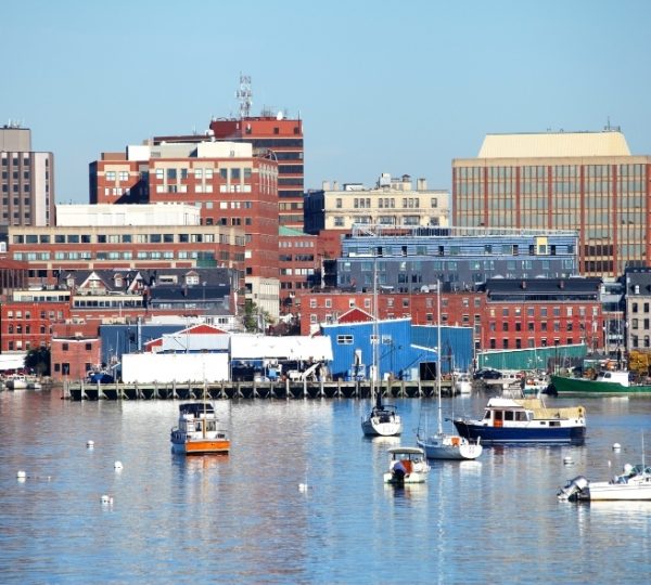 Portland Hafenpanorama in Maine: ruhiges blaues Wasser, Bootsbewohner vor roten Backsteingebäuden, farbenfrohe Hafenhäuser und Bootskutter am Kai Kanada-Rundreise