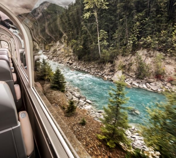 Der Blick aus dem Panoramafenster zeigt ein türkisfarbenes Flusstal in den Rocky Mountains, umgeben von dichtem Wald und mit Fahrtatmosphäre auf der Kanada Zugreise. Kanada-Rundreise