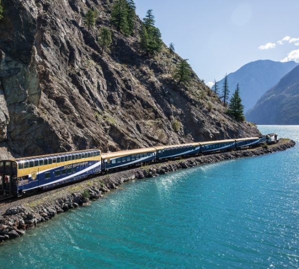 Türkisblaues Wasser und felsige Küste an den Rocky Mountains, während der Rocky Mountaineer Zug mit Panoramafenstern vorbeifährt. Kanada-Rundreise