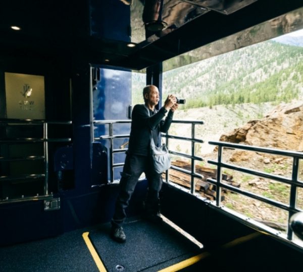 Im Rocky Mountaineer mit Panoramafenster zieht eine spektakuläre Bergkulisse durch die Rocky Mountains, draußen grünes Tal und klare Naturstimmung. Kanada-Rundreise