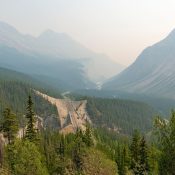 Blick auf den geöffneten Icefields Parkway durch die bewaldete Berglandschaft im Jasper Nationalpark nach dem Waldbrand Kanada-Rundreise